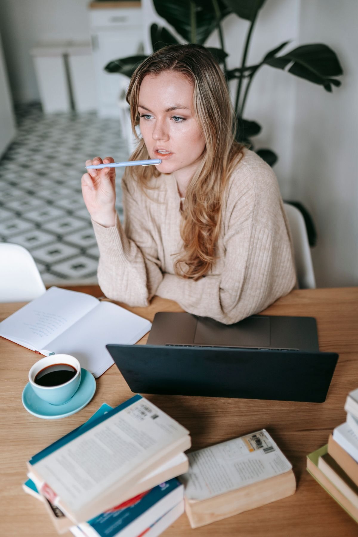 Professional at a desk pausing to think beside a notebook and laptop