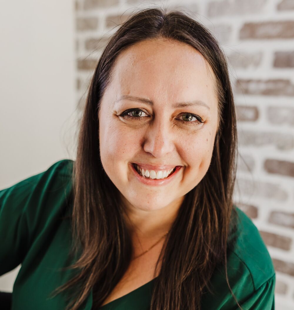Michelle Polk smiling in front of a white brick wall